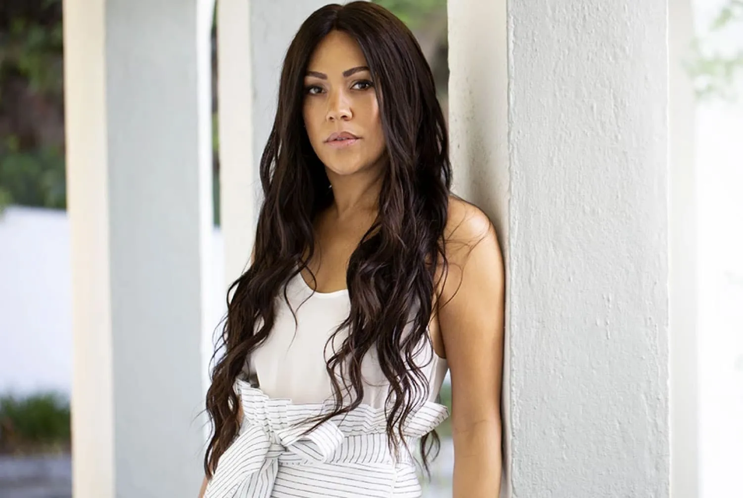 Portrait of Shani Darden leaning against a white column